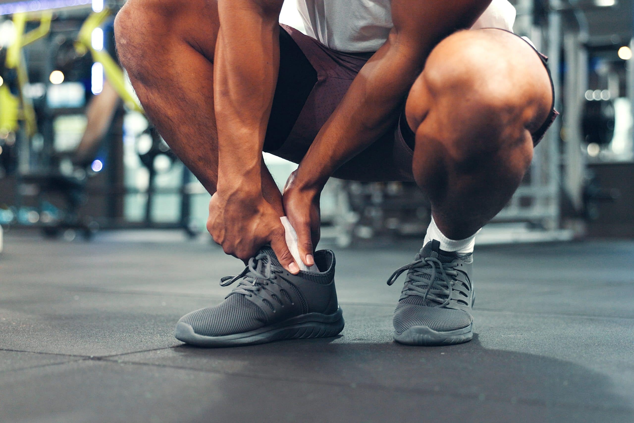 Man in gym holding his ankle following an injury