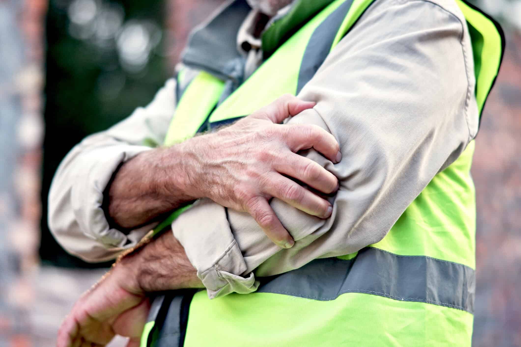 Construction worker in hi-vis vest holding his elbow after an injury