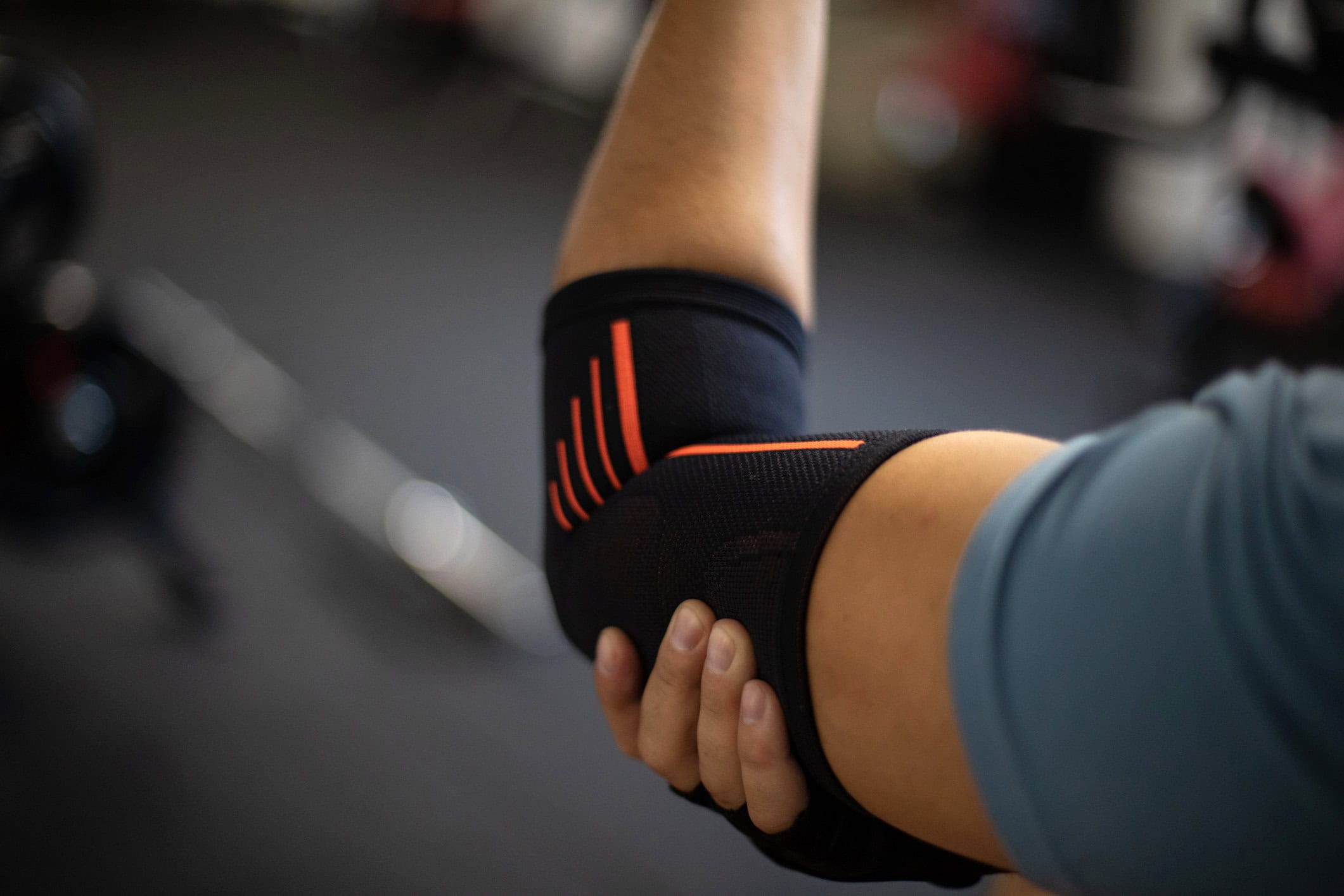 Man at the gym wearing an elbow support and holding his painful elbow